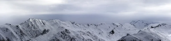 Panoramic view on high snowy mountains and sunlight storm sky be