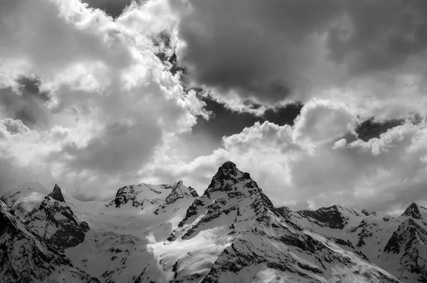 Black and white view on evening mountains in sunlight clouds