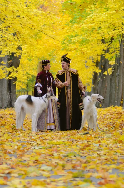 Couple in traditional medieval costumes with two borzoi dogs