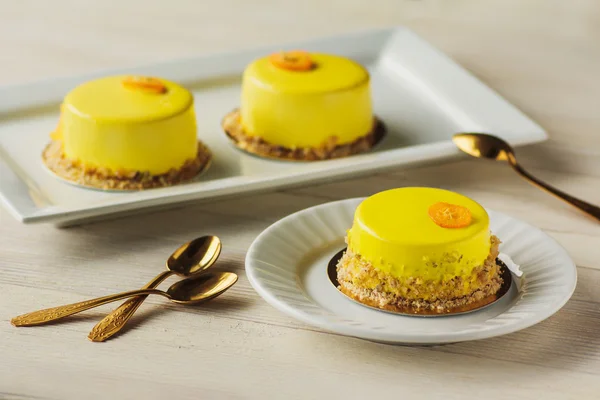 Mini mousse cakes covered with yellow glaze. Modern european cak