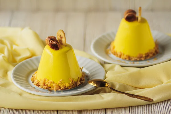 Mini mousse cakes with banana covered with yellow glaze. Modern