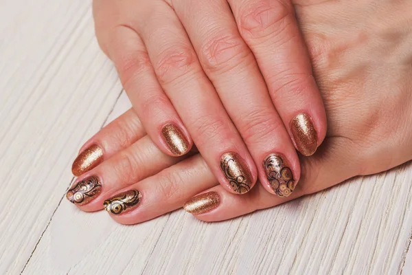 Gold nail art with black painted swirls