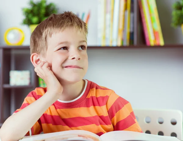 Elementary school boy at desk reading boock