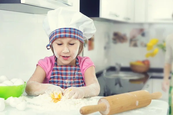 Cute little girl in apron baking cookies at home kitchen
