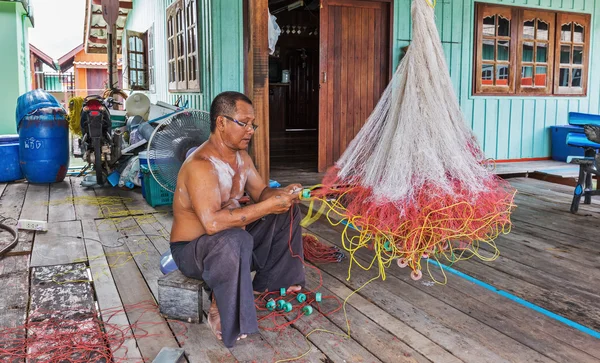 Man weave a fishing net in the village