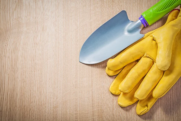 Safety gloves hand spade on wooden board gardening concept