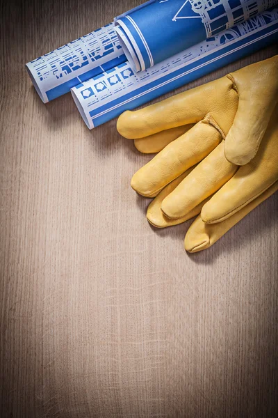 Blue blueprints leather protective gloves on wooden board constr
