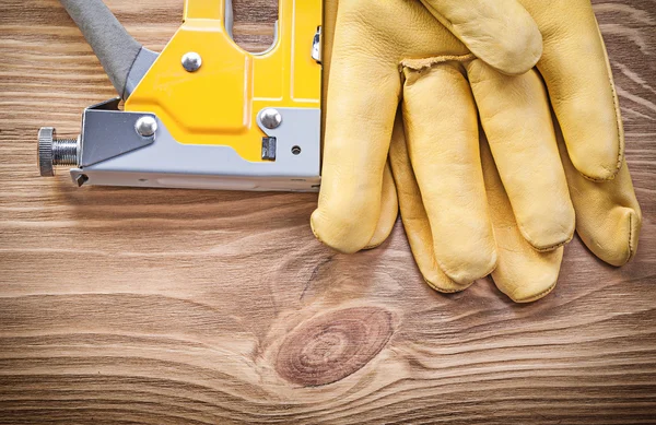 Straple gun safety gloves on wood board top view construction co