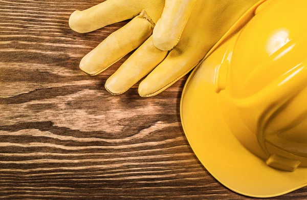 Yellow protective gloves building helmet on wooden board constru