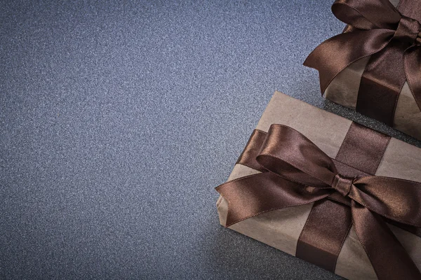 Giftboxes in brown wrapping paper on grey background celebration