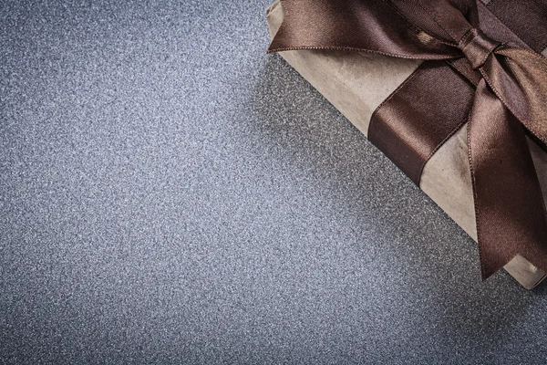 Packaged present with brown bow on grey background celebrations
