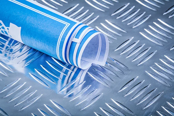 Blue rolled blueprints on corrugated metal background constructi