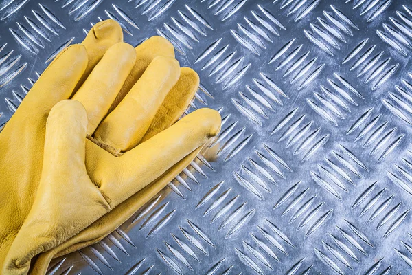 Pair of leather safety gloves on fluted metal sheet construction