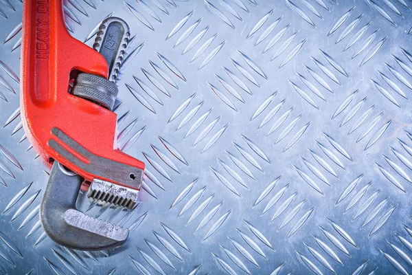 Red adjustable monkey wrench on corrugated metallic sheet copysp