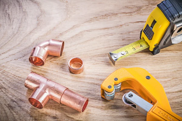 Composition of brass pipe cutter fittings measuring tape on wood