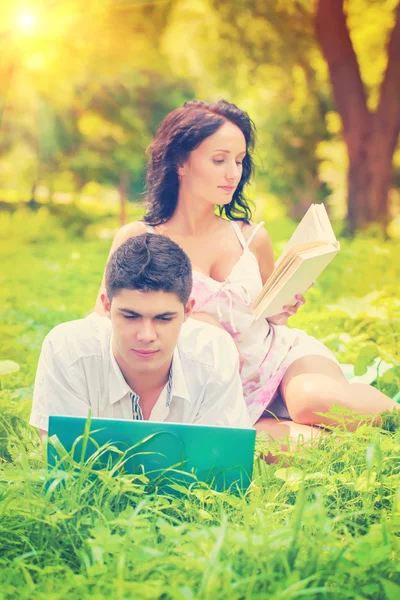 Resting couple with laptop and book in park on grass instagram c