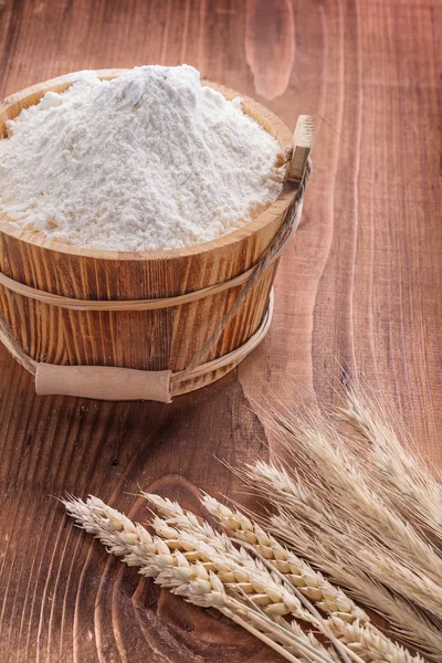 Flour in wooden bucket and ears of wheat