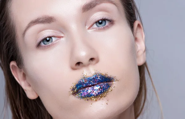 Beautiful model with natural make-up and blue glitter lips