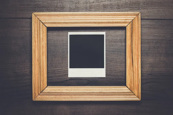 Empty frame and old photo on wooden background