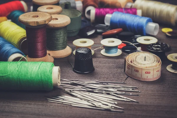 Needles buttons and threads on brown wooden table