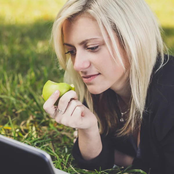 Student girl with laptop studying in park