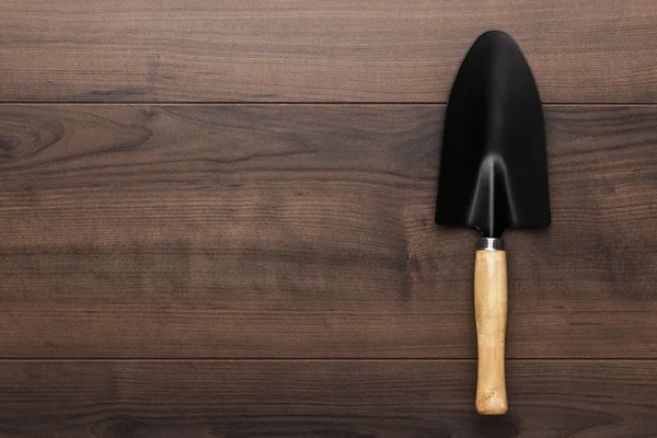 Black gardening shovel on the wooden table