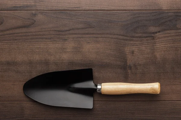 Black gardening shovel on the wooden table