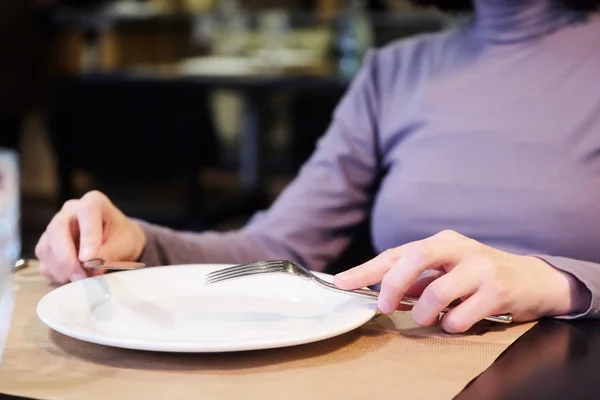 Female hands at dinner table holding fork