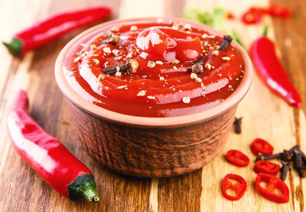 Red chilli pepper sauce on wooden background