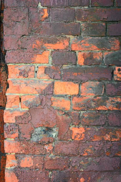 Obsolete brick wall painted in orange and dark violet