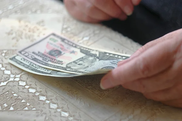 Retired woman with small amount of money on table, toned image, colorized, selective focus, very shallow dof. SEnior woman counting dollars