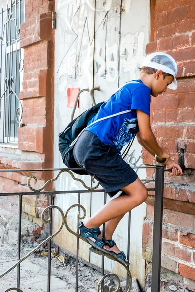 Child boy climbing over metal fence