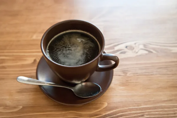 A  cup of coffee in a brown cup on wood background