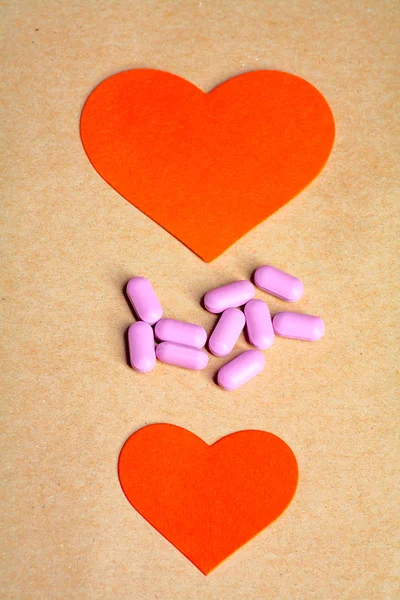 Two paper hearts and heart pills in the center