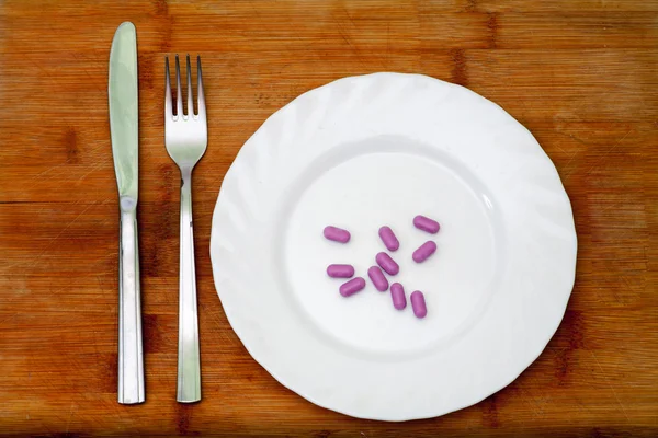 Diet. Violet pills on plate