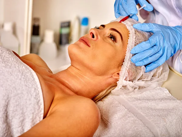 Lying woman middle-aged in spa salon with beautician. Woman gets botox injections.