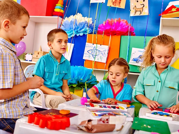 Group kids mold from plasticine  in kindergarten .