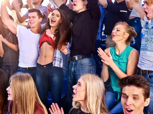 Sport fans clapping and singing on tribunes.