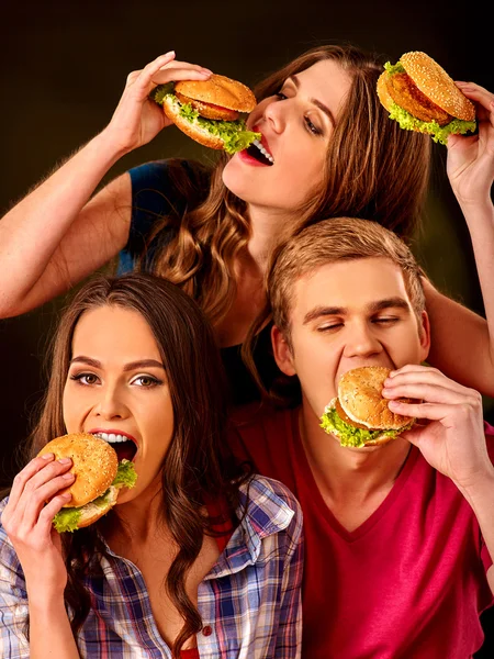 Group people eats with relish hamburgers .