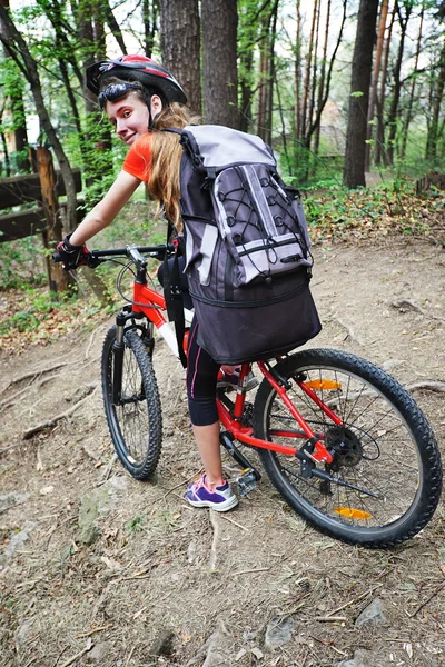 Bikes cycling girl into park. Girl wearing helmet and big backpack