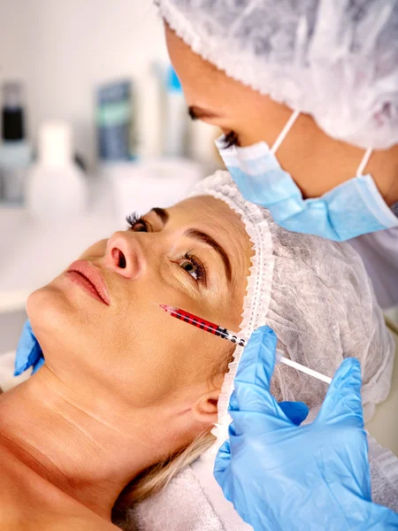 Woman middle-aged in spa salon giving botox injections.
