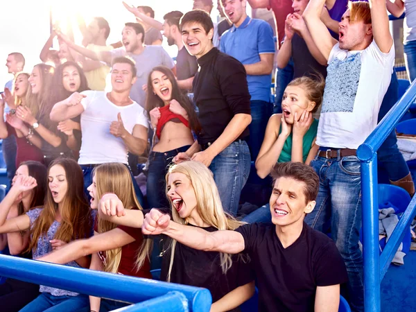 Sport fans hands up and singing  on tribunes.