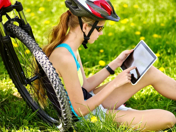 Bikes cycling girl wearing helmet  in cycling sitting near bicycle and watch pc tablet.