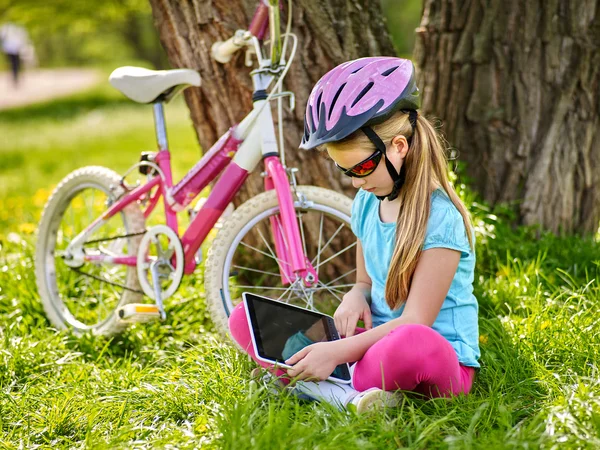 Bikes cycling girl wearing helmet  in cycling sitting near bicycle and watch pc tablet.