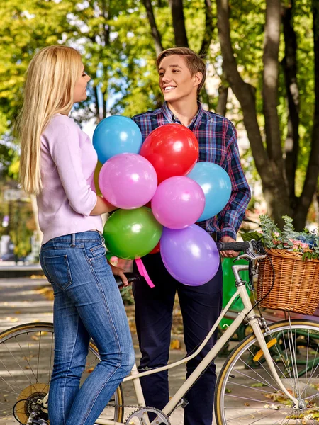 Couple with balloons  on retro bike in park.