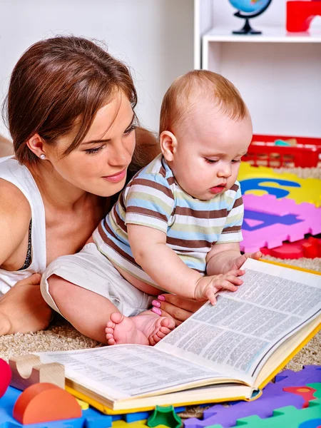 Kid with mother baby boy on floor and read book.