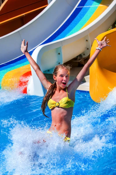 Child on water slide at aquapark show thumb up.