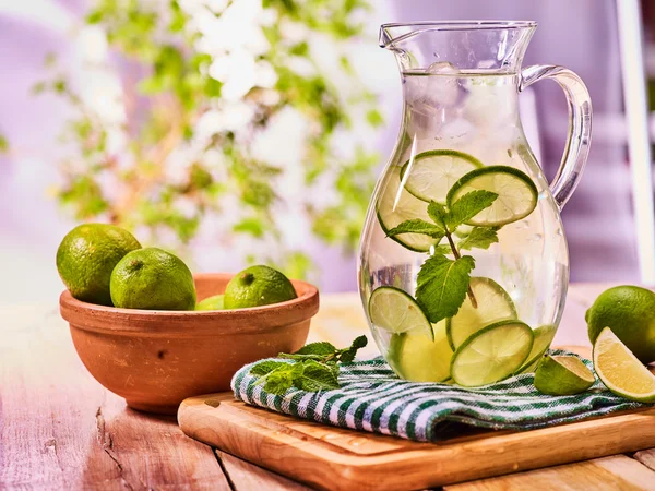 On wooden table is glass jug with transparent drink.