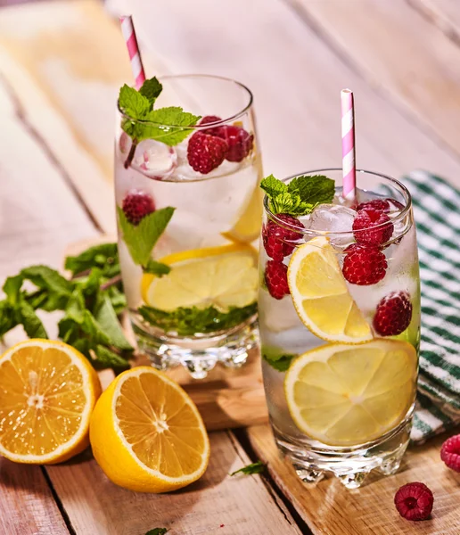 Wooden boards is glass with ice cubes and berries cocktail .