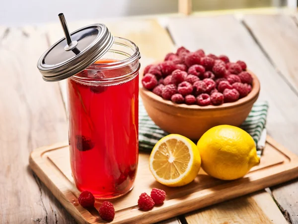 Ice cold drink glass with raspberry and lemon cocktail .